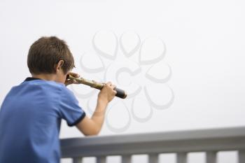 Royalty Free Photo of a Preteen Boy Leaning on a Railing Looking Through a Telescope