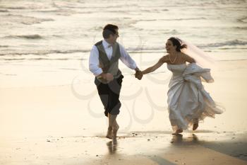 Royalty Free Photo of a Groom and Bride Running Barefoot on a Beach