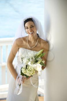 Caucasian mid-adult bride holding bouquet laughing.