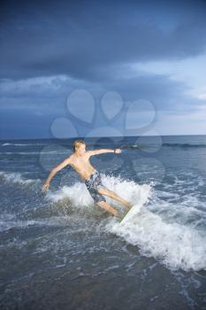 Royalty Free Photo of a Teenager Riding a Skimboard
