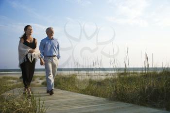 Royalty Free Photo of a Couple Holding Hands and Walking Down a Walkway at a Beach