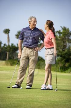 Royalty Free Photo of a Man and Woman Standing on a Golf Course Talking to Each Other