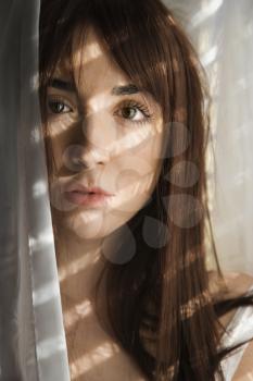 Royalty Free Photo of a Woman Standing in Sunlit Curtains