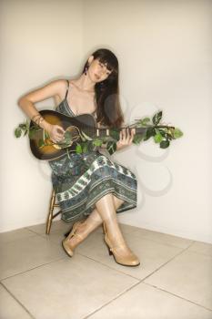 Royalty Free Photo of a Woman Sitting Playing Guitar