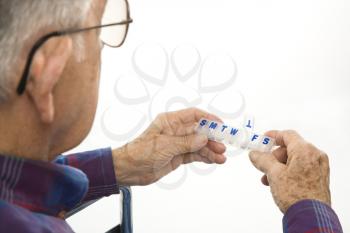 Royalty Free Photo of an Elderly Man Holding Seven-Day Pill Box With Thursday Open