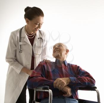 Royalty Free Photo of a Doctor Looking at An Elderly Man in a Wheelchair 