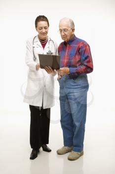 Mid-adult Caucasian female doctor showing papers to elderly Caucasian male.