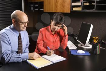 Royalty Free Photo of a Businessman and Businesswoman in an Office Going Over an Appointment Calendar