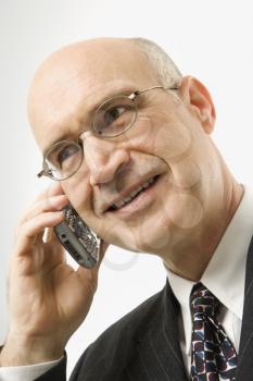 Smiling Caucasian middle-aged businessman talking on cellphone against white background.
