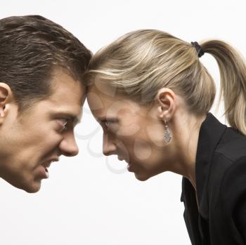 Royalty Free Photo of a Businessman and Businesswoman With Foreheads Together Wearing Hostile Expressions