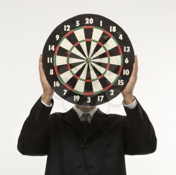 Royalty Free Photo of a Man Wearing a Suit and Holding a Dartboard in Front of His Face