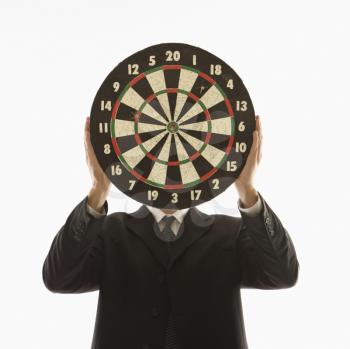 Royalty Free Photo of a Man Wearing a Suit and Holding a Dartboard in Front of His Face