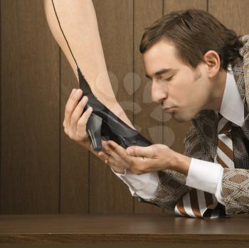 Royalty Free Photo of a Man Holding a Woman's Shoe and Preparing to Kiss it