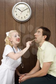 Royalty Free Photo of a Female Nurse Examining a Male's Mouth With a Tongue Depressor