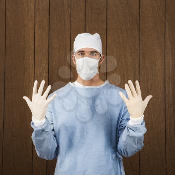 Royalty Free Photo of a Male Surgeon Wearing a Face Mask and Holding Up Gloved Hands