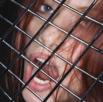 Royalty Free Photo of a Woman Behind a Fence With Her Mouth Open