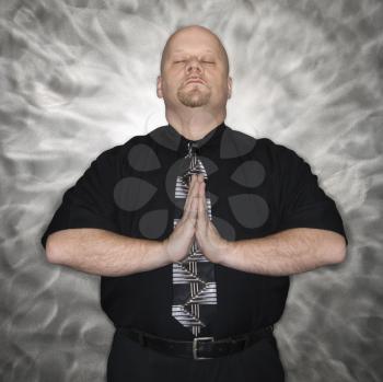 Royalty Free Photo of a Man Standing With Hands Together and Eyes Closed in a Meditative Position