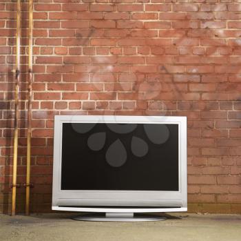 Royalty Free Photo of a Flat Panel Television Set in Front of a Red Brick Wall