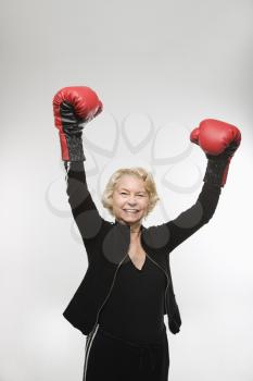 Royalty Free Photo of an Older Woman Wearing Boxing Gloves Raised in the Air