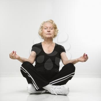 Royalty Free Photo of an Older Woman Sitting in Yoga Position on Floor Meditating