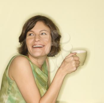 Pretty Caucasian mid-adult woman holding up coffee cup and smiling.