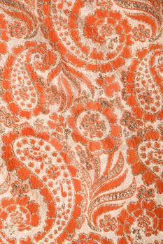 Royalty Free Photo of a Close-Up of Orange Textural Vintage Fabric With Paisley and Metallic Thread Stitching