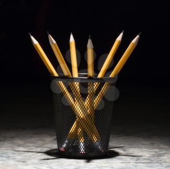 Group of pencils in a wire mesh pencil holder.