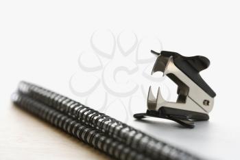 Royalty Free Photo of a Staple Remover on Top of an Open Spiral Bound Notebook