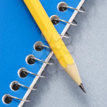 Royalty Free Photo of a Sharp Pencil Placed on a Blue Spiral Bound Notebook