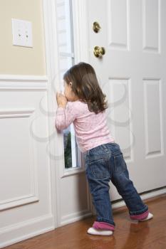 Royalty Free Photo of a Girl Toddler Peeking Out Through the Door