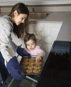 Royalty Free Photo of a Mother and Daughter Taking Cookies out of the Oven