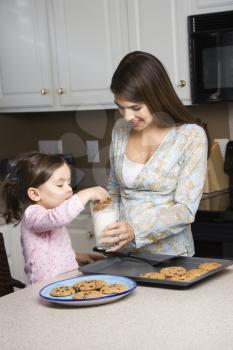 Royalty Free Photo of a Mother Holding a Glass of Milk While Her Daughter Dunks a Cookie