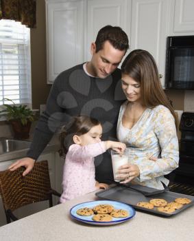 Royalty Free Photo of a Mother and Father Watching Their Daughter Eat Cookies