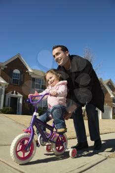 Royalty Free Photo of a Father Helping His Daughter Ride a Bicycle