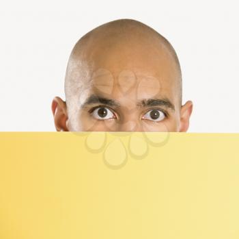 Royalty Free Photo of a Man Peeking Over a Blank Yellow Sign