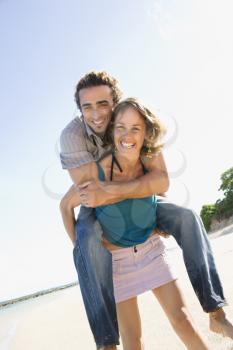 Royalty Free Photo of a Woman Giving a Man a Piggyback Ride on a Beach