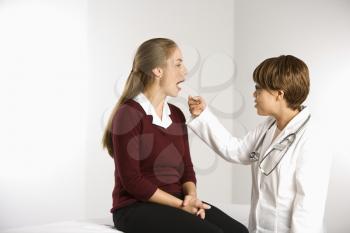 Royalty Free Photo of a Doctor Examining a Female Patient With a Tongue Depressor