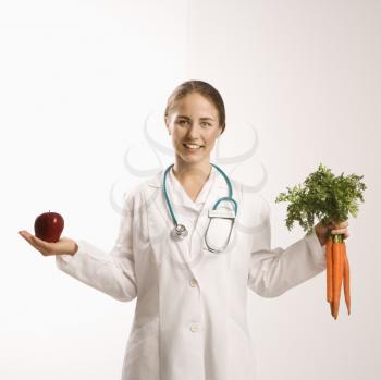 Royalty Free Photo of a Doctor Holding an Apple and a Bunch of Carrots