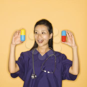 Royalty Free Photo of a Doctor Holding Up Giant Pills Smiling