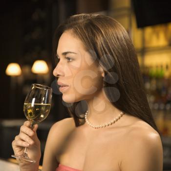 Royalty Free Photo of a Woman Sitting at a Bar Drinking a Glass of White Wine