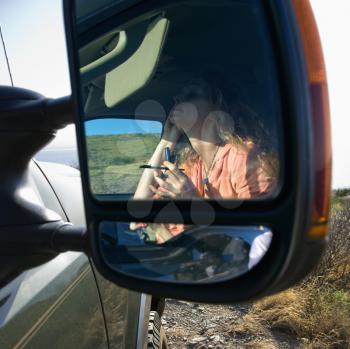 Royalty Free Photo of a Reflection in a Vehicle Mirror of a Woman Applying Mascara