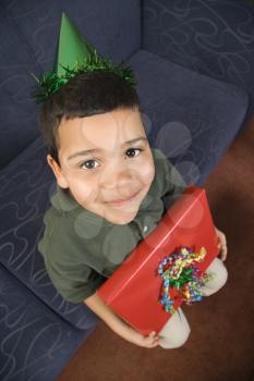 Royalty Free Photo of a Boy Wearing a Party Hat Holding a Present and Smiling