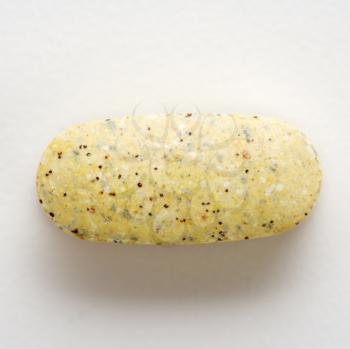 Royalty Free Photo of a Close-Up of Brown Speckled Caplet Against a White Background