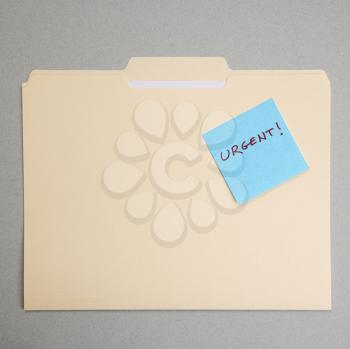 Royalty Free Photo of a Folder With a Sticky Note Attached Reading Urgent