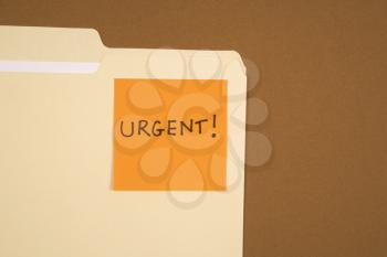 Royalty Free Photo of a Folder With an Orange Sticky Note Attached Reading Urgent