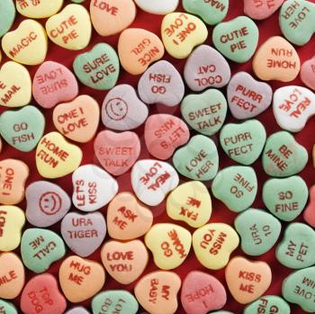 Royalty Free Photo of a Group of Candy Hearts With Sayings on Them Arranged on Red Background