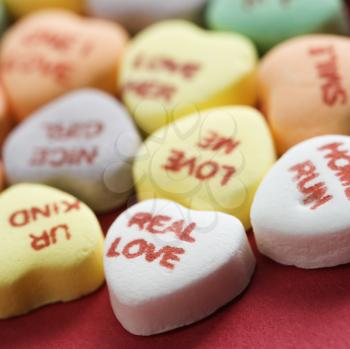 Colorful candy hearts with sayings on them arranged on red background.