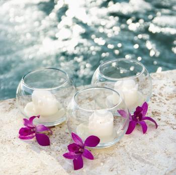 Royalty Free Photo of Three Candles and Three Purple Orchids by a Pool