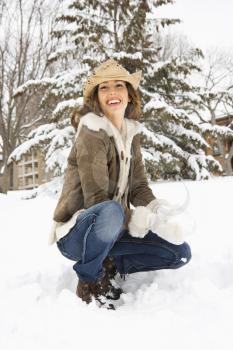 Royalty Free Photo of a Woman Kneeling in the Snow With a Snowball and Wearing a Cowboy Hat