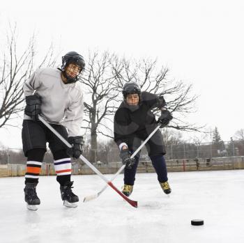 Royalty Free Photo of Two Boys in Ice Hockey Uniforms Playing Hockey on the Ice Rink